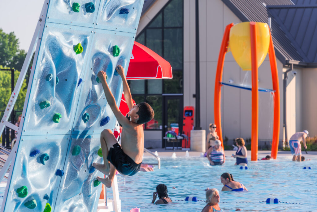 Photo of a child using one of the climbing walls at the YMCA Water Park at The Landing in Bettendorf, Iowa.